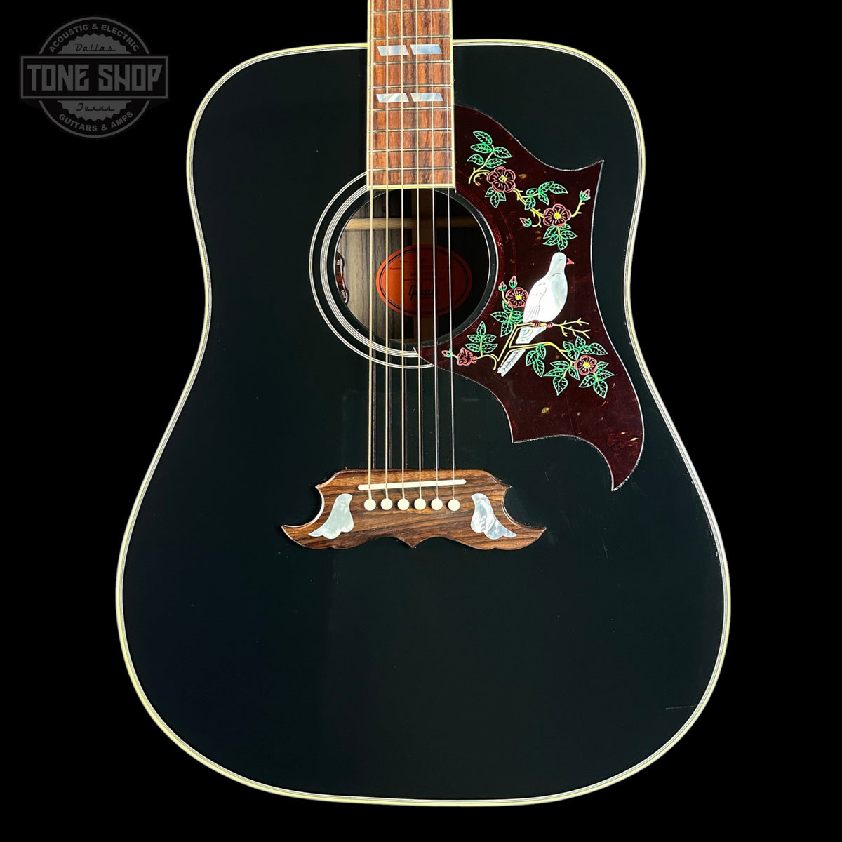Acoustic guitar with decorative inlay on a black background, featuring the Tone Shop logo.