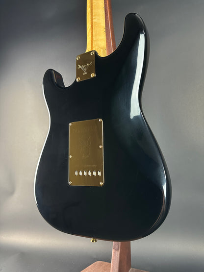 Black electric guitar with gold hardware on a gray background