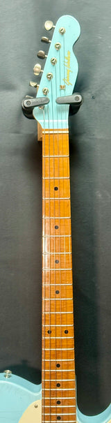 Close-up of a guitar neck with a light blue headstock on a dark background