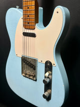 Blue electric guitar with a white pickguard on a black background