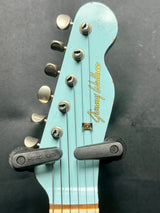 Close-up of a guitar headstock with 'Jimmy Iovine' branding on a dark background