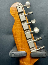 Close-up of a guitar headstock with tuning pegs on a dark background