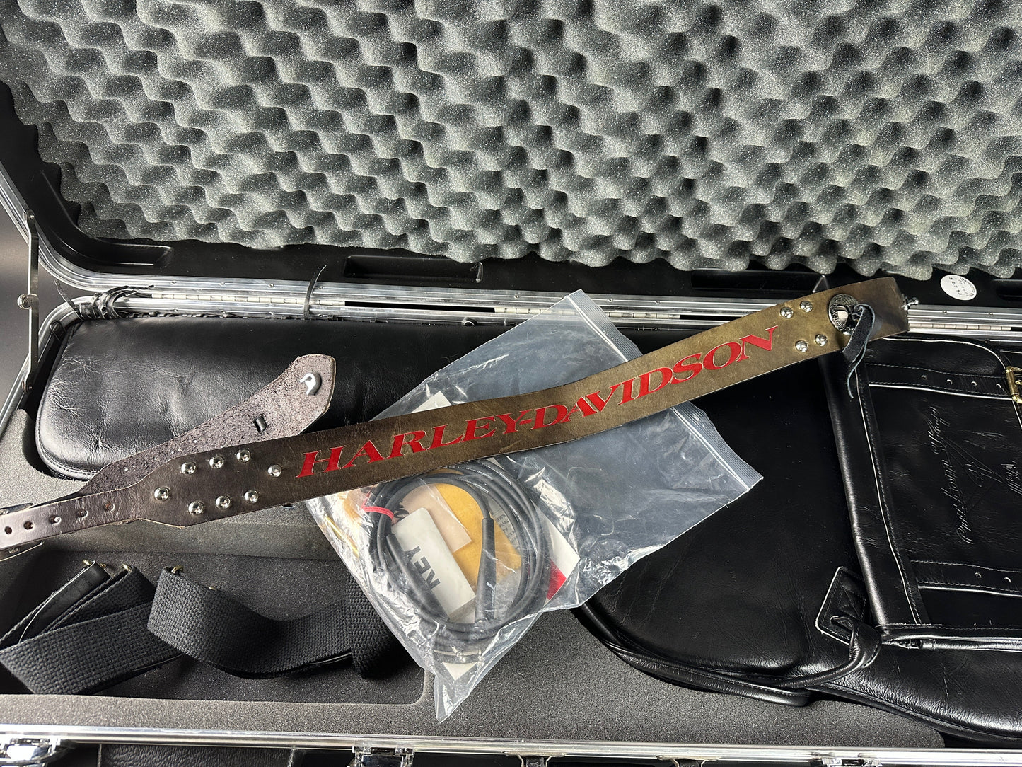 Harley-Davidson belt on a black leather bag with a textured gray background