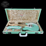 Turquoise electric guitar in an open case with Fender logo