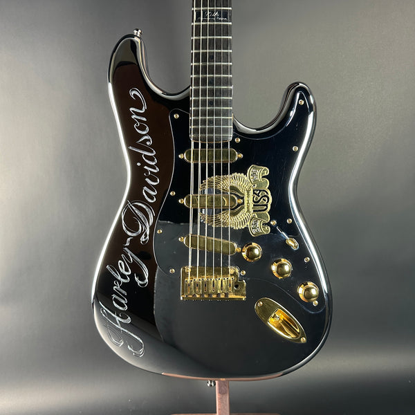 Black electric guitar with gold accents on a gray background