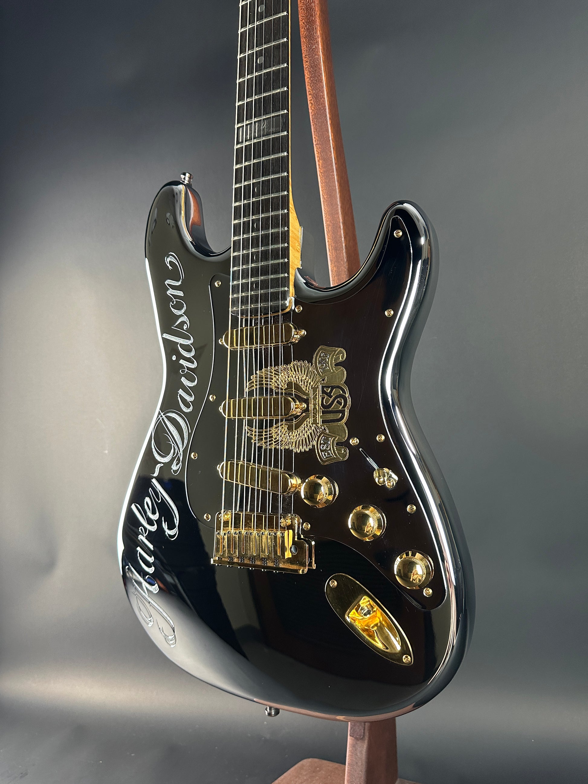 Black electric guitar with gold hardware on a gray background
