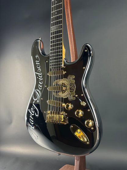 Black electric guitar with gold hardware on a gray background