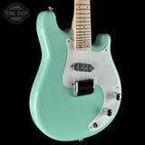 Turquoise electric guitar with a white pickguard on a black background, featuring 'Tone Shop' branding.