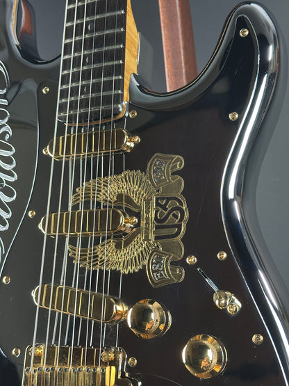 Close-up of a black electric guitar with gold hardware and logo.