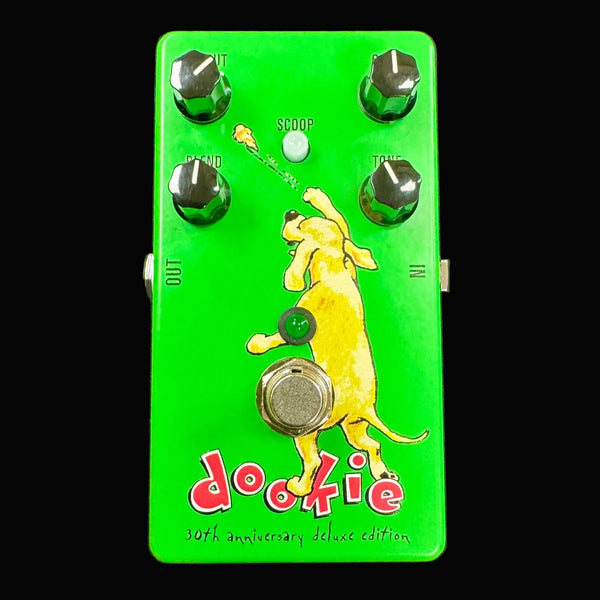 Green guitar effects pedal with a dog illustration throwing a turd and 'dookie' branding on a gray background