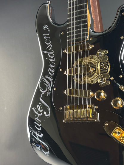 Close-up of a black electric guitar with gold hardware on a gray background