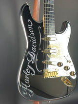 Close-up of a black electric guitar with gold hardware on a gray background