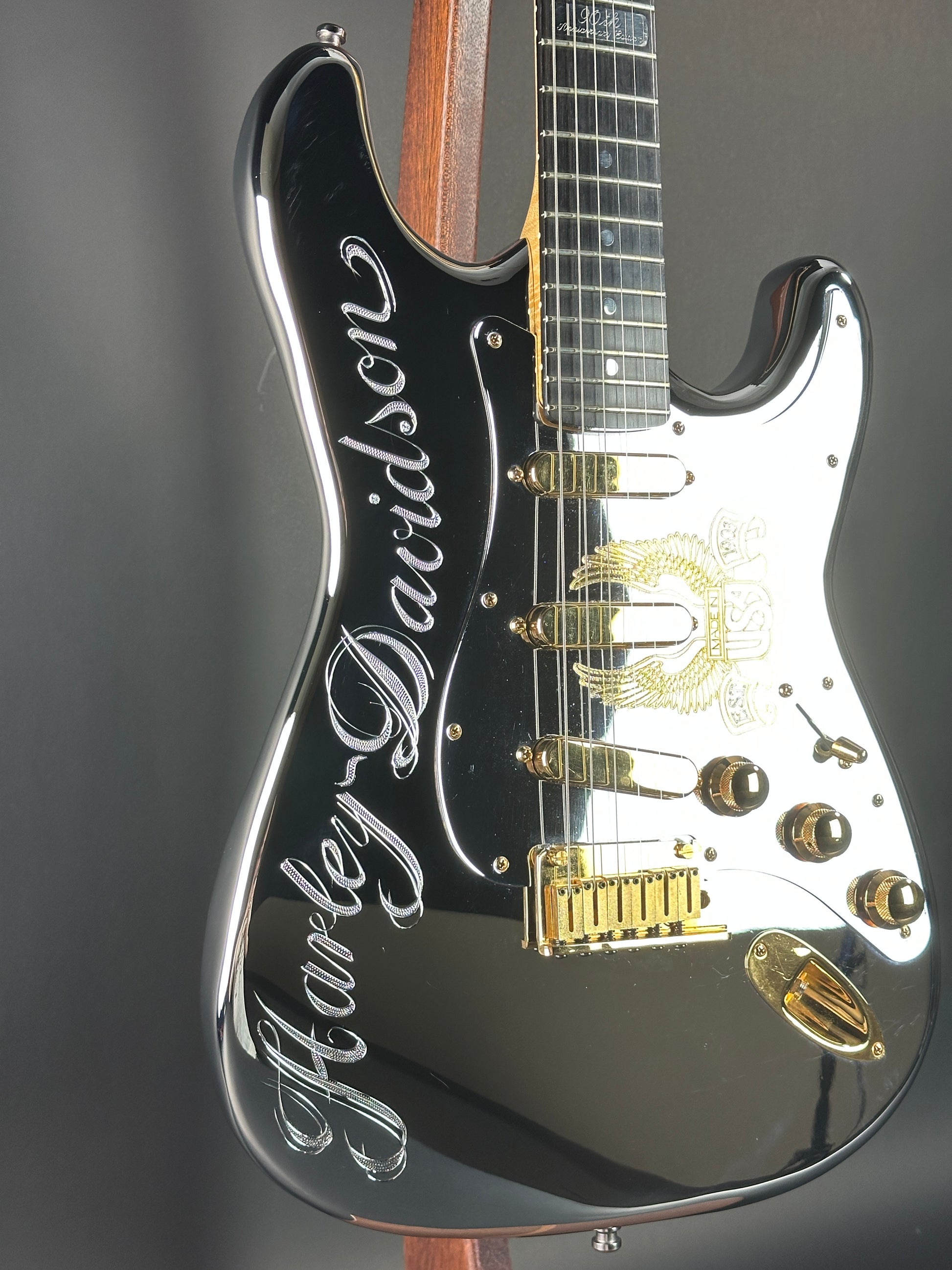 Close-up of a black electric guitar with gold hardware on a gray background