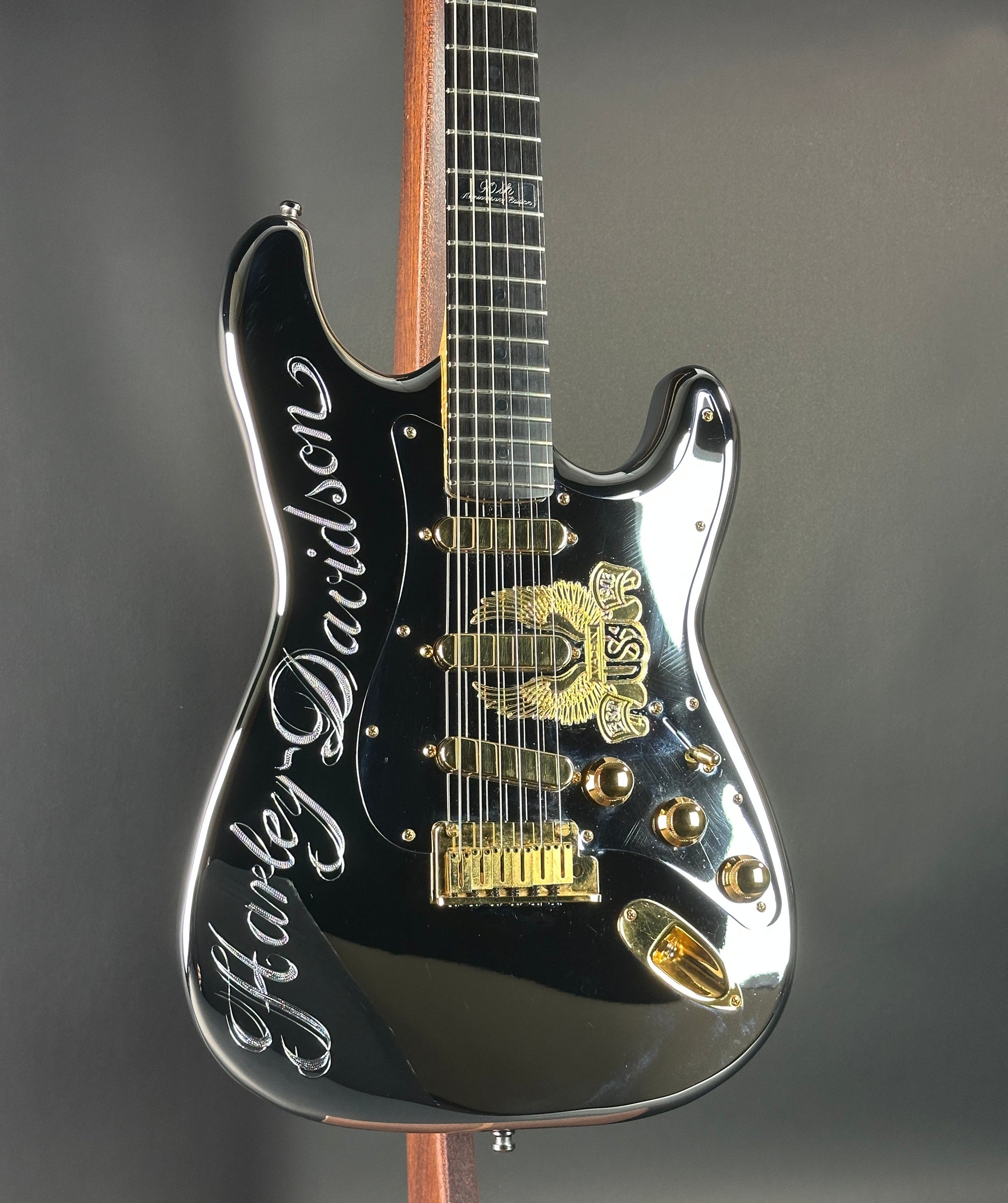 Black electric guitar with gold details on a gray background