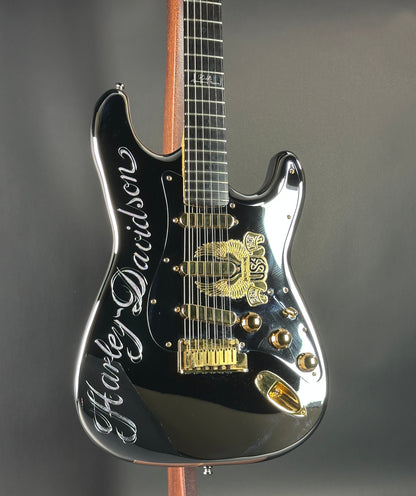 Black electric guitar with gold details on a gray background