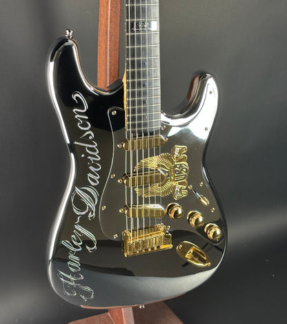 Black electric guitar with gold hardware on a dark background