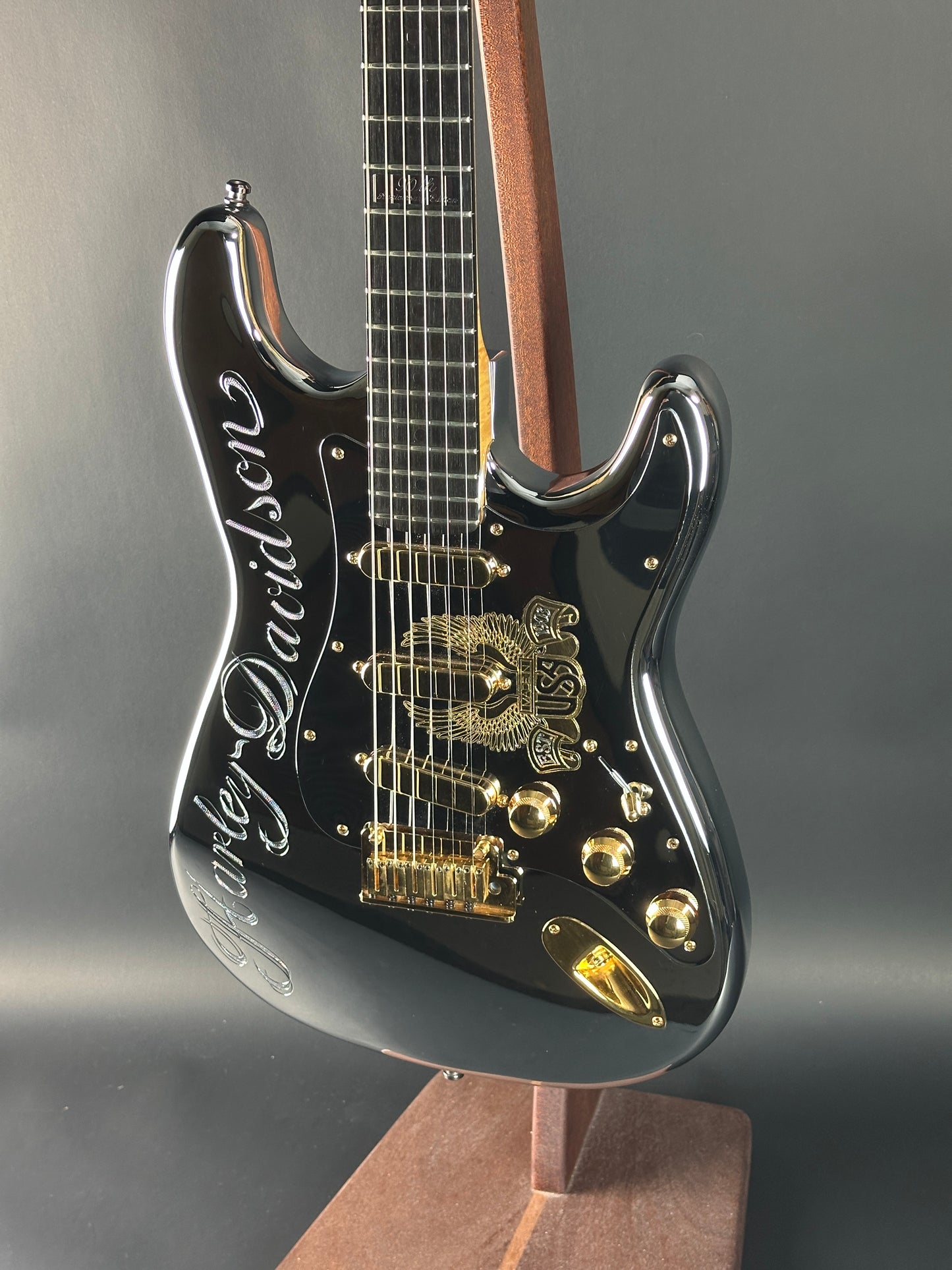 Close-up of a black electric guitar with gold hardware on a gray background