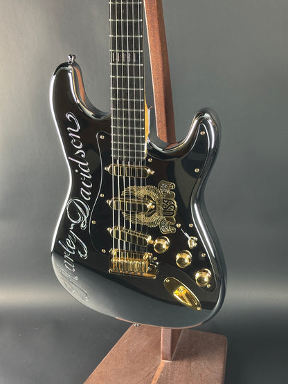 Close-up of a black electric guitar with gold hardware on a gray background