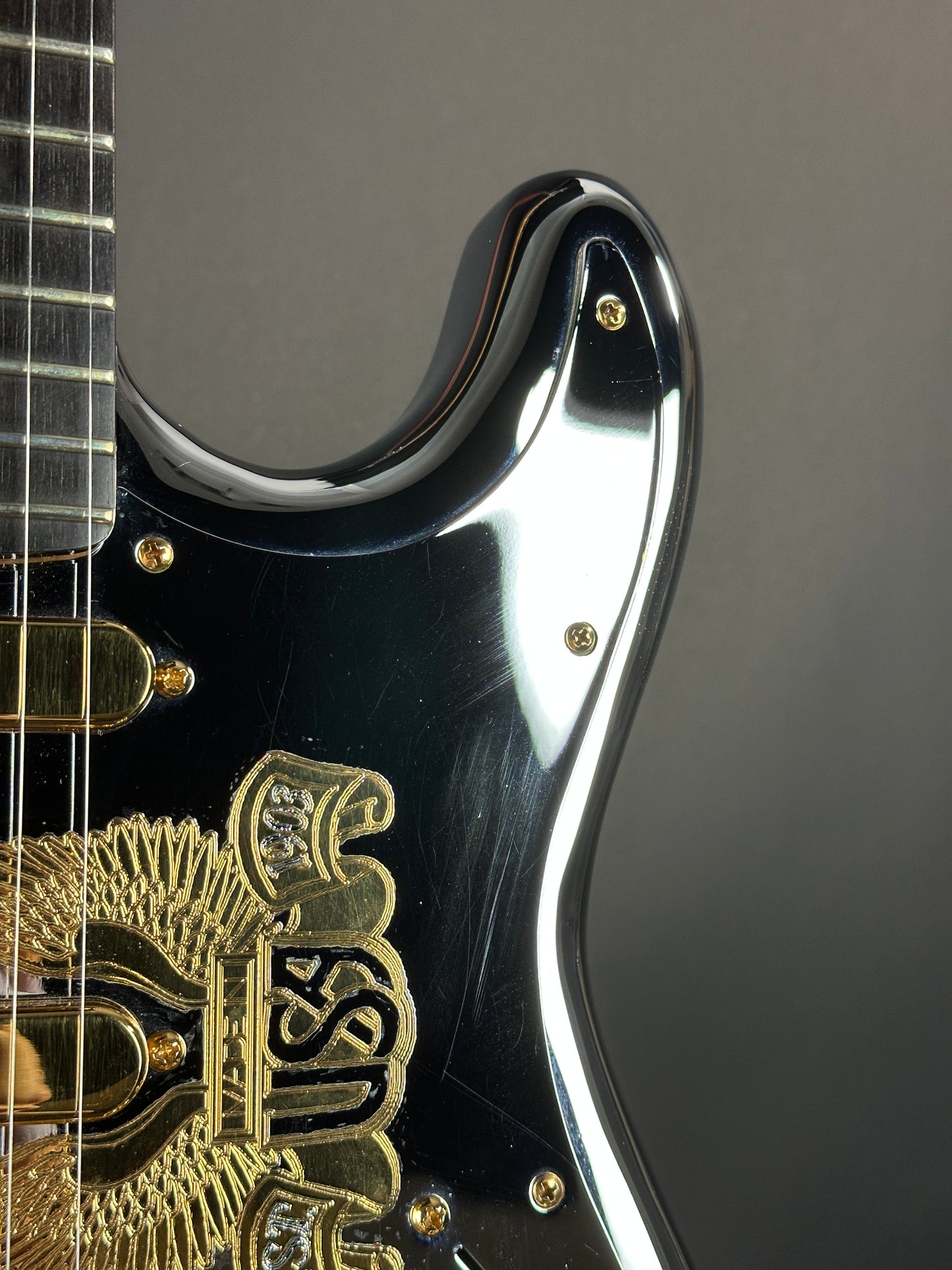 Close-up of a guitar's headstock with brand logo on a dark background