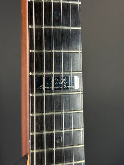 Close-up of a guitar fretboard with brand name on a dark background