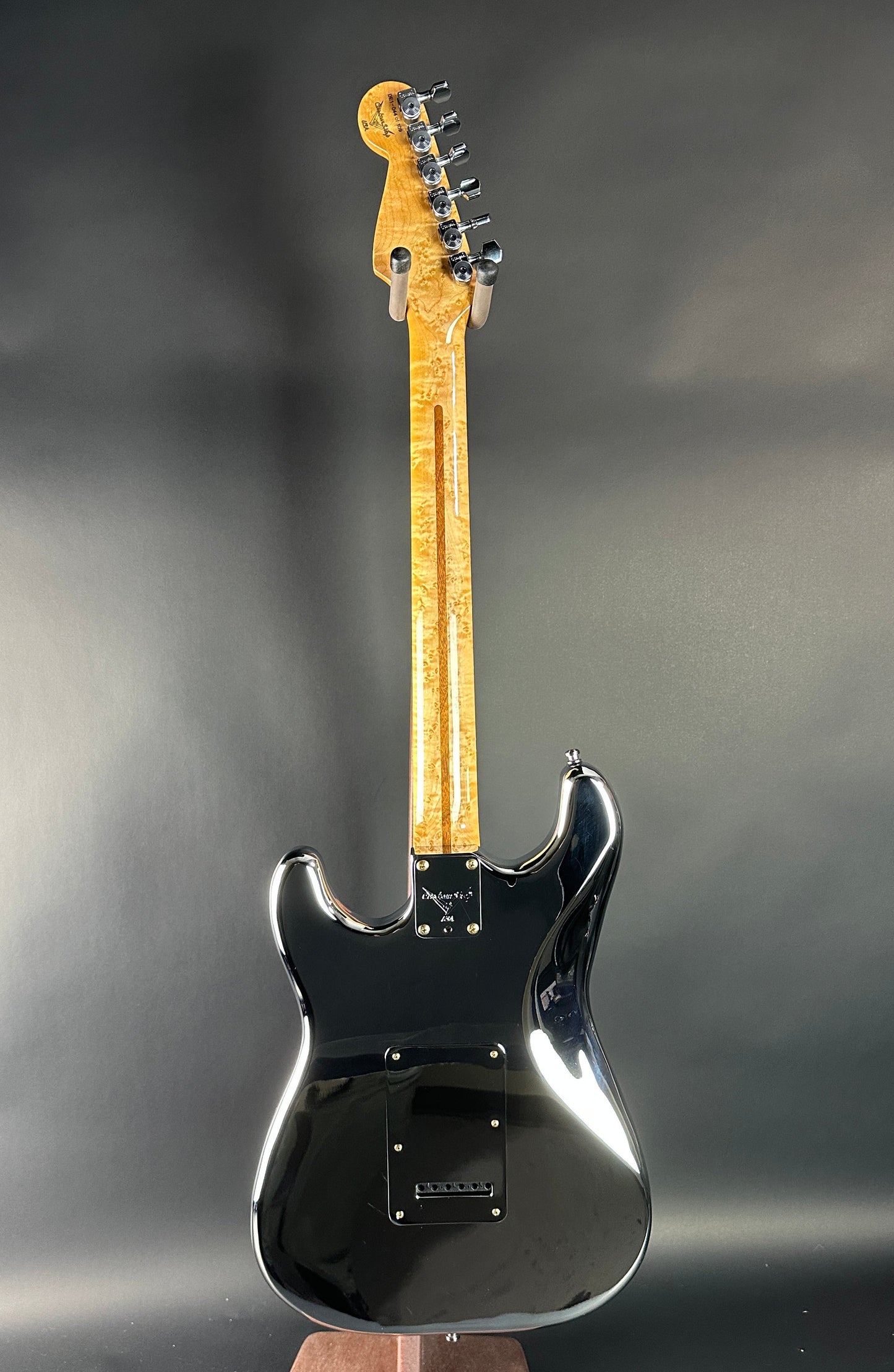 Black electric guitar on a reflective surface with a dark background