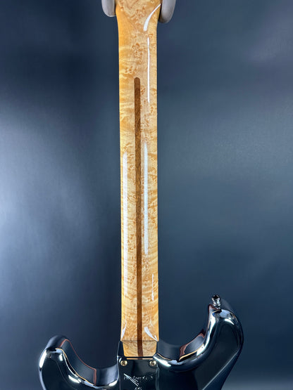 Close-up of a guitar neck with a pickguard on a dark background