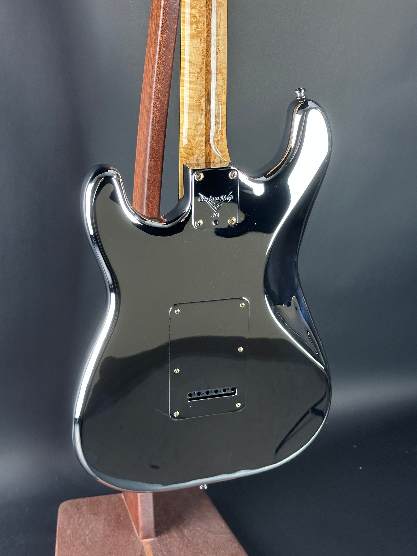 Close-up of a guitar's neck and headstock on a dark background