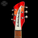 Close-up of the headstock of a Ricken Basso electric guitar against a solid black background, showing the red and orange wood grain finish, silver tuning pegs, and white headstock with black lettering.