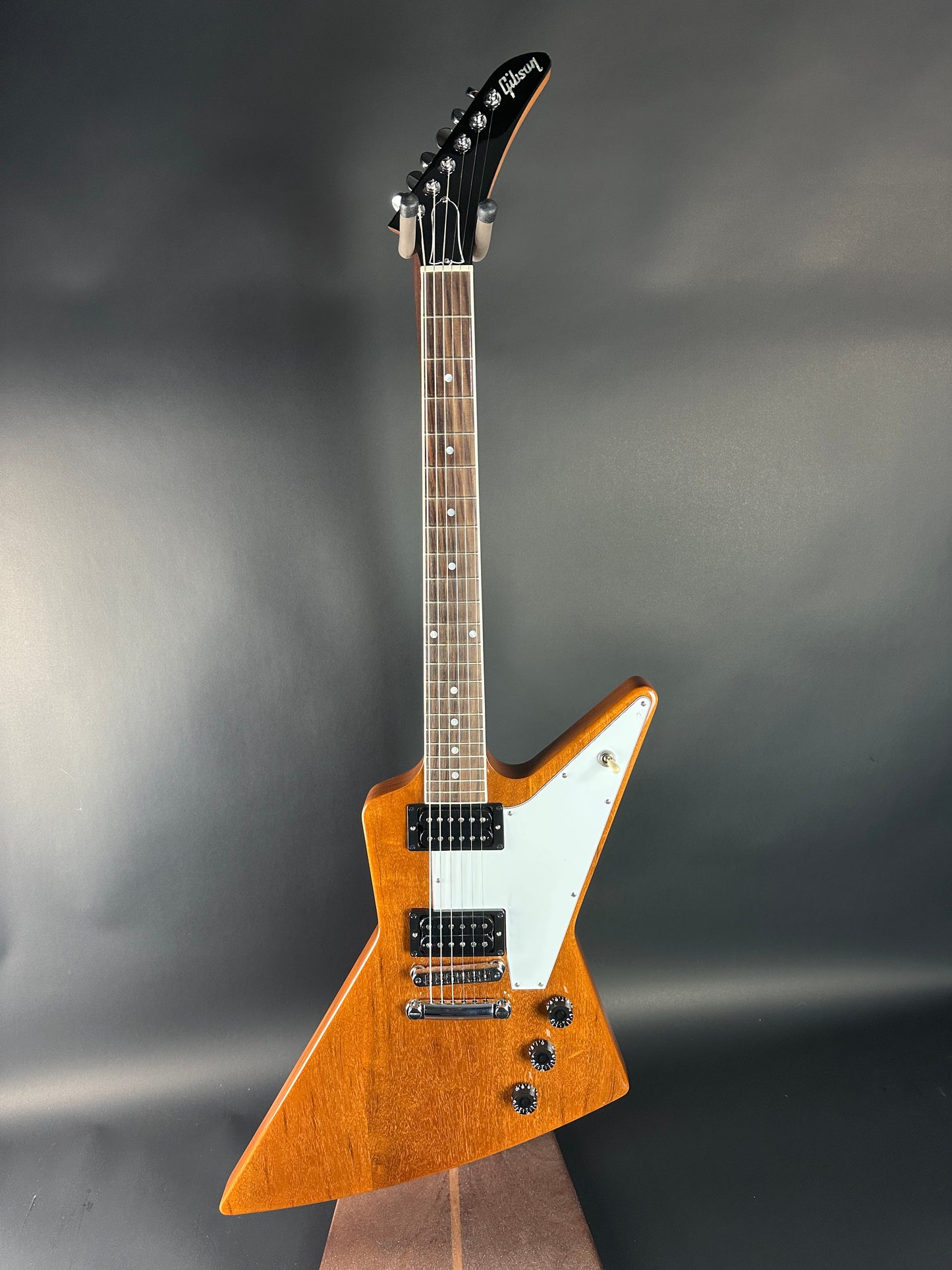 Wooden electric guitar with a white pickguard on a dark background