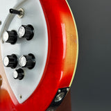 Close-up of the side control panel of an electric guitar featuring a red and gold sunburst finish, a white pickguard, and black control knobs.