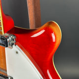 Close-up of an electric guitar body showing a glossy red-orange sunburst finish, a white pickguard, and part of the wooden neck against a dark gray background.