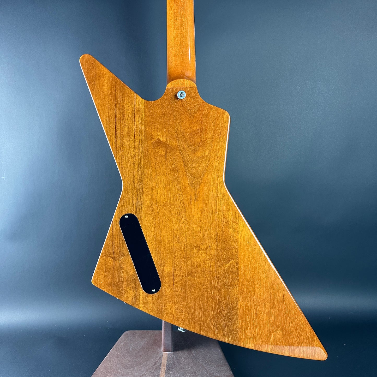 Wooden guitar body on a stand against a blue background