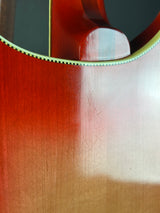 Close-up of an acoustic guitar body showing the glossy reddish-brown wood finish, sound hole, and light-colored edge trim.