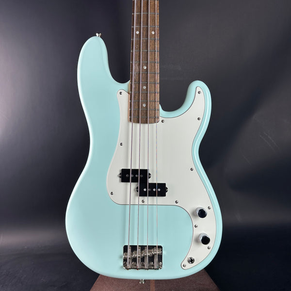 Light blue electric bass guitar on a dark background