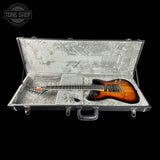 An electric guitar with a sunburst finish resting inside an open hard case with a gray foam interior, shown against a black background with a Tone Shop watermark in the top-left corner.