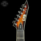 Close-up of the headstock of a Fender Lucilex electric guitar, featuring a sunburst finish that transitions from amber-orange to black, with chrome tuning pegs and a black pickguard labeled 'EC-20'.