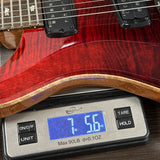 Red electric guitar on a digital scale displaying weight