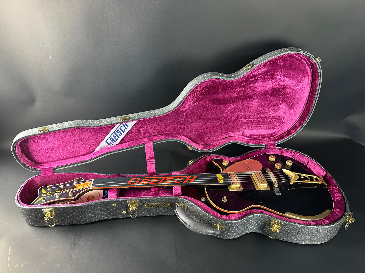 Gretsch guitar in a pink-lined case on a dark background