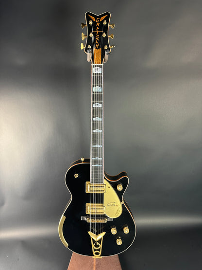 Black electric guitar with gold accents on a gray background