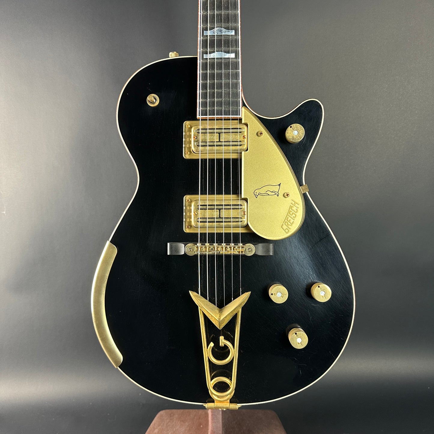 Black electric guitar with gold accents on a gray background