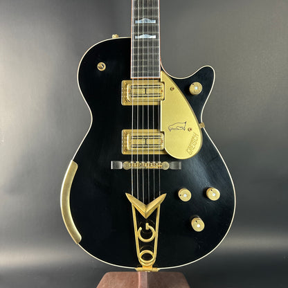 Black electric guitar with gold accents on a gray background