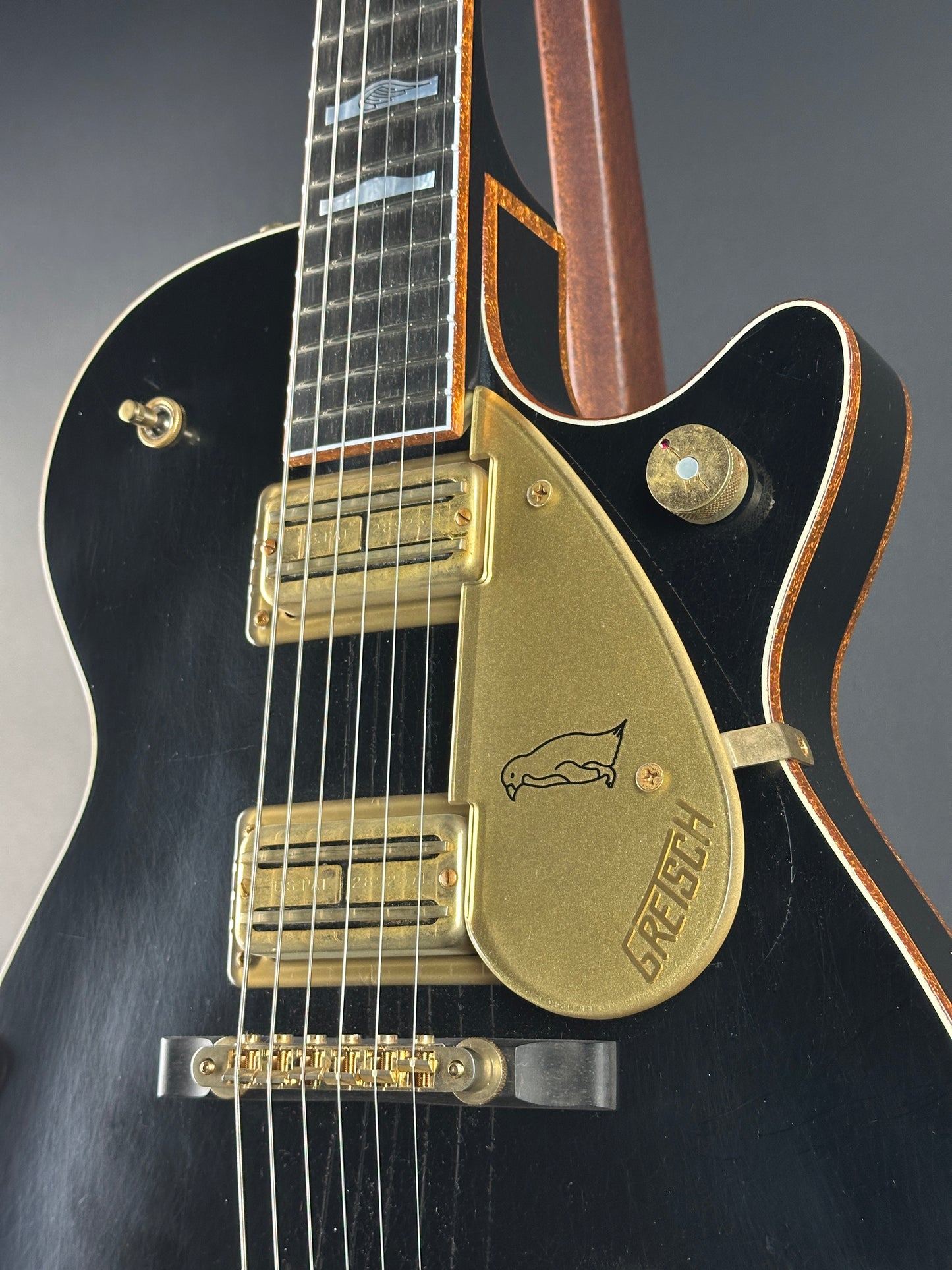 Close-up of a guitar with a gold pickguard and 'PRS' branding on a dark background.