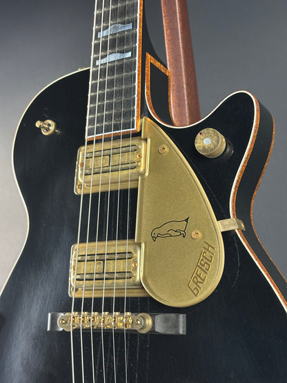 Close-up of a guitar with a gold pickguard and 'PRS' branding on a dark background.