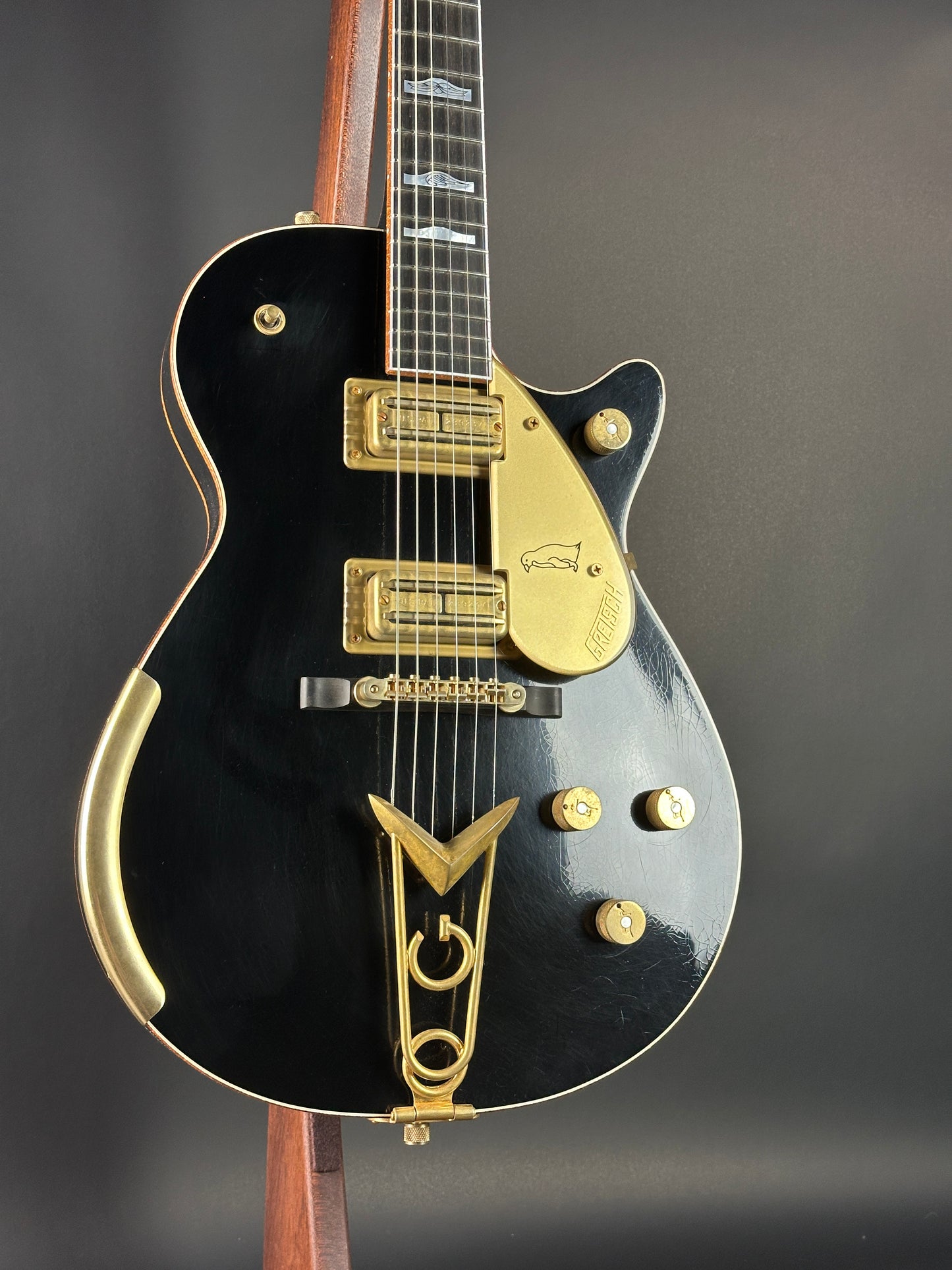 Black electric guitar with gold details on a dark background