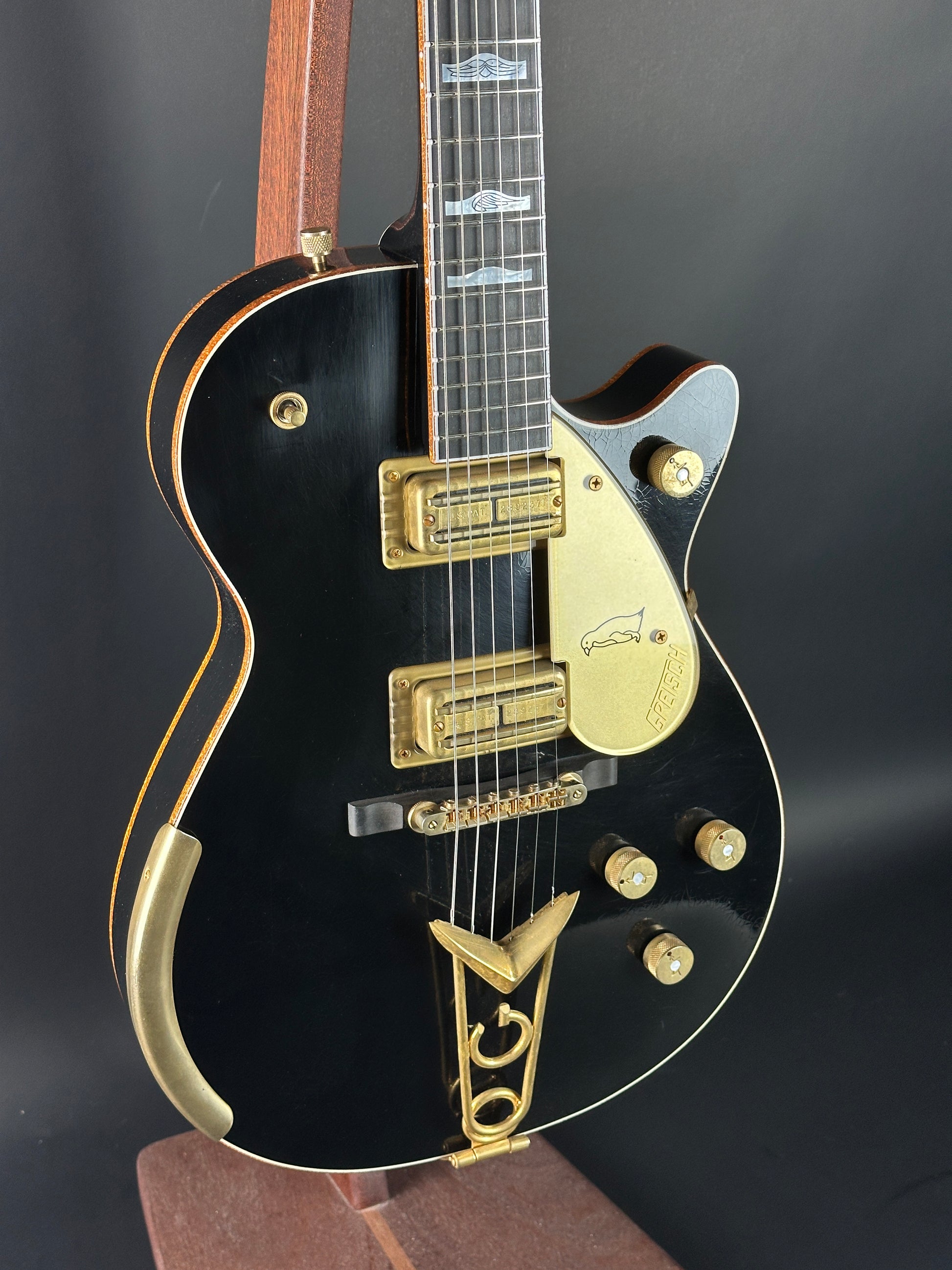 Black electric guitar with gold hardware on a dark background