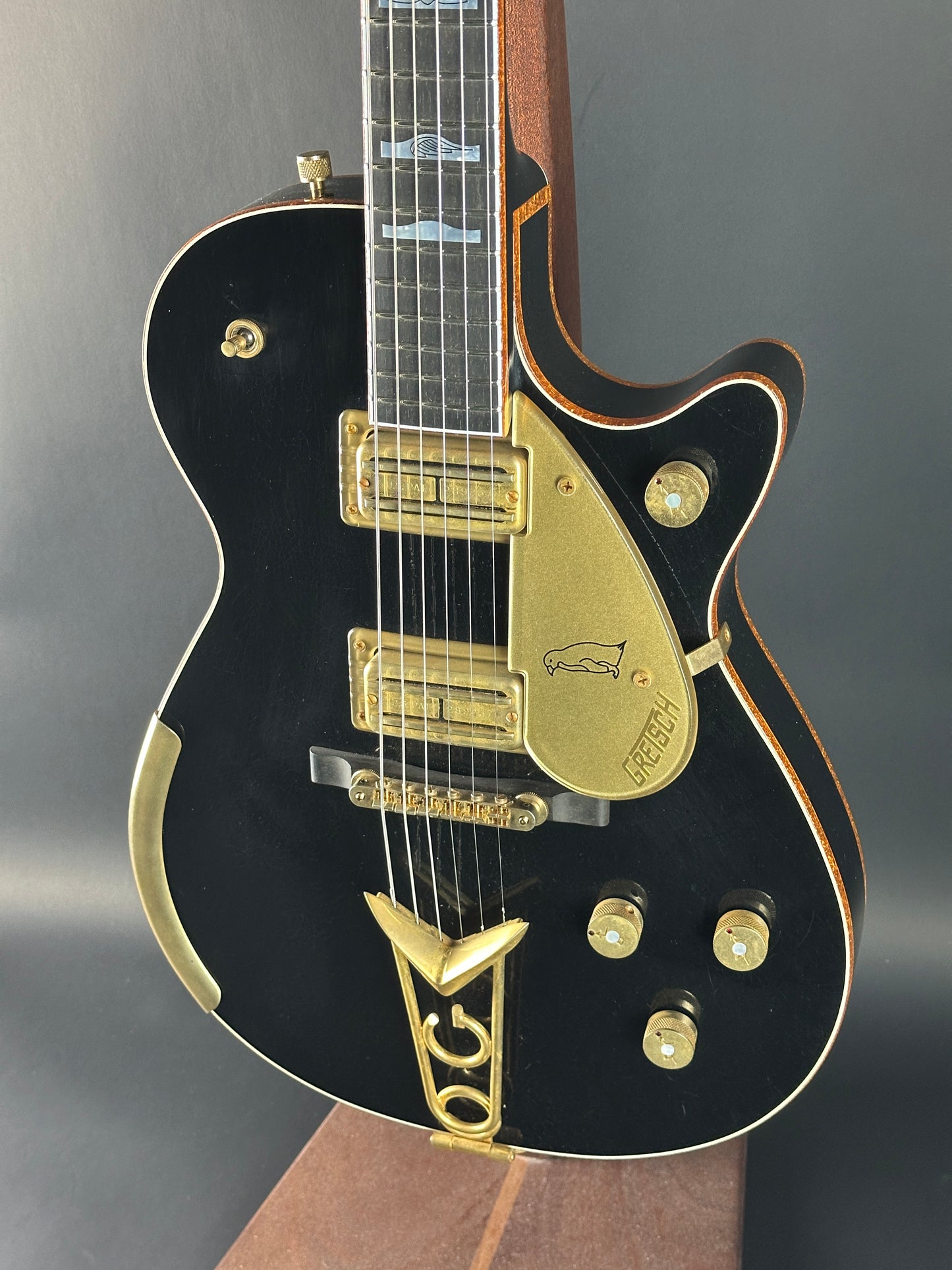 Black electric guitar with gold hardware on a gray background