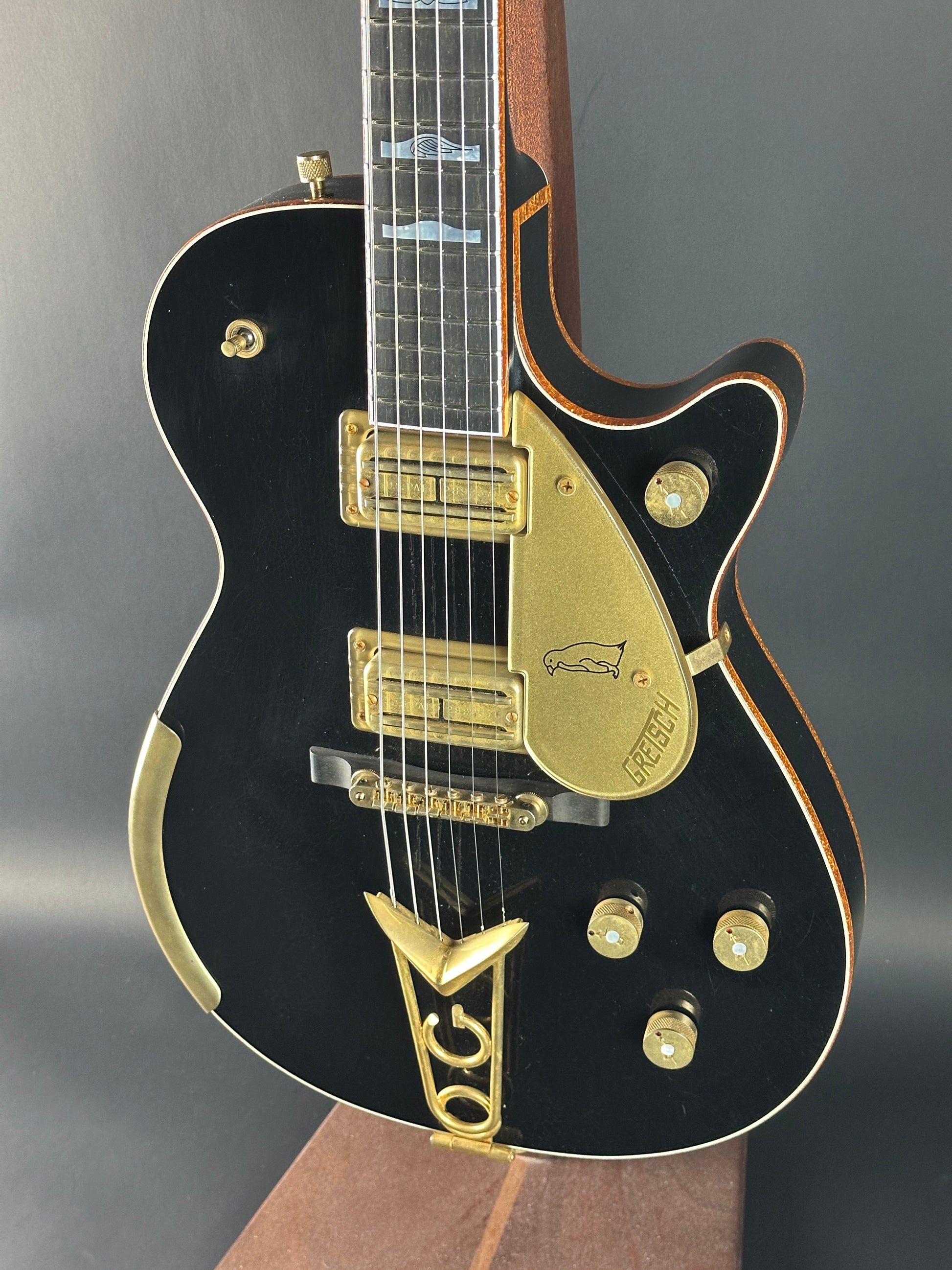 Black electric guitar with gold hardware on a gray background
