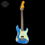 A Fender Stratocaster electric guitar with a distressed blue body, cream pickguard, and yellow headstock, shown against a solid black background with a Tone Shop watermark in the top-left corner.