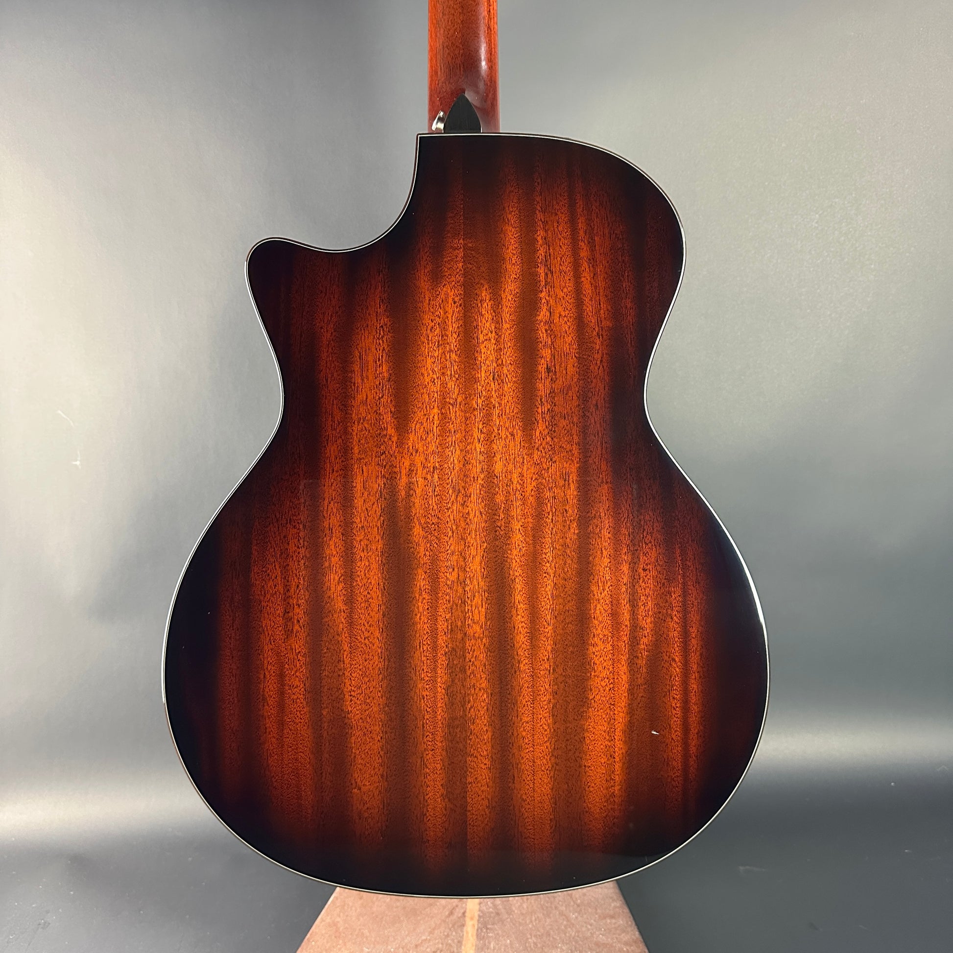 Back view of a guitar with a brown finish on a gray background