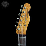 Close-up of a Fender Coronet Classic electric guitar headstock, showing the wood grain finish and six tuning pegs against a black background.